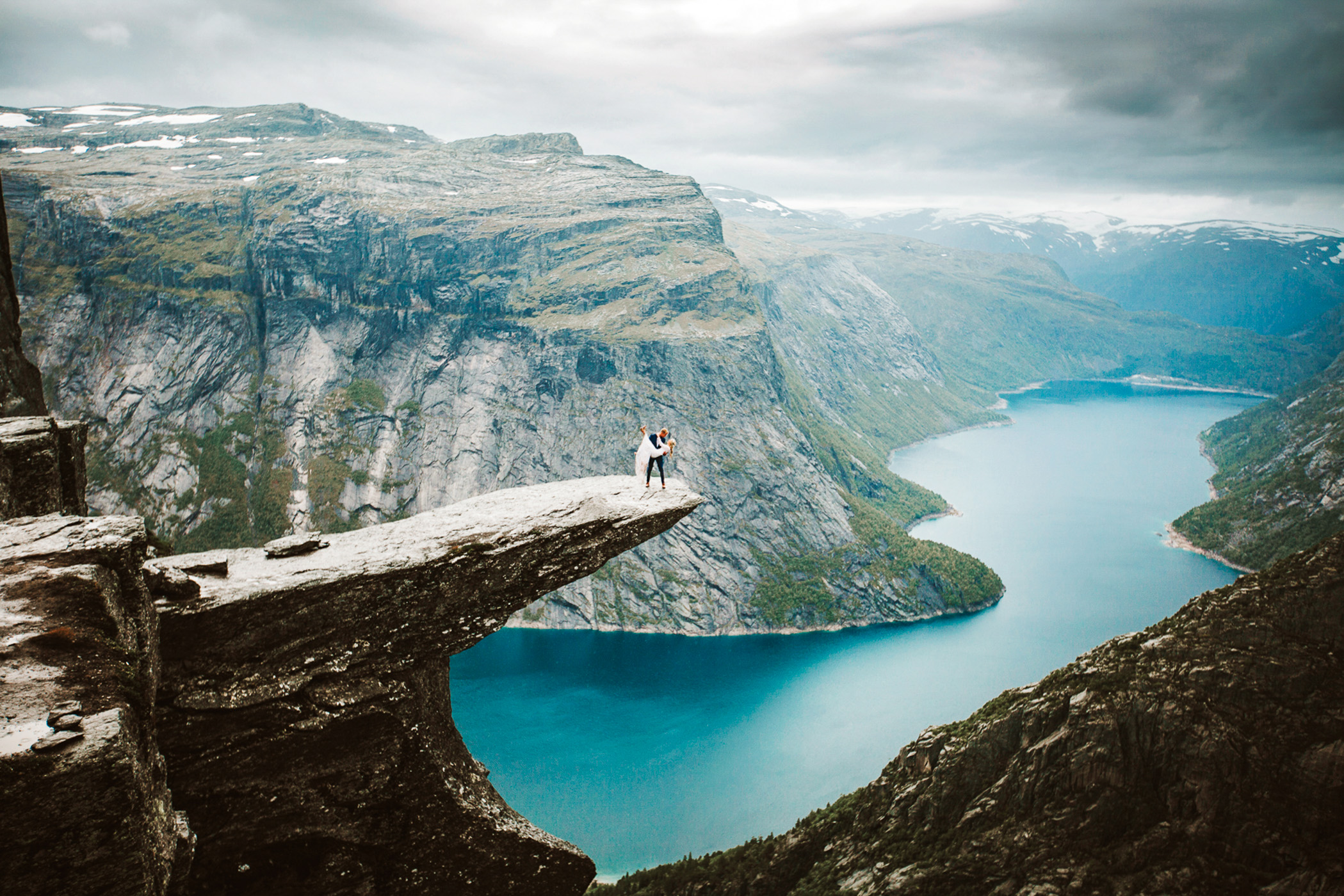 Couple standing on the Trolltunga ledge above a Norwegian fjord