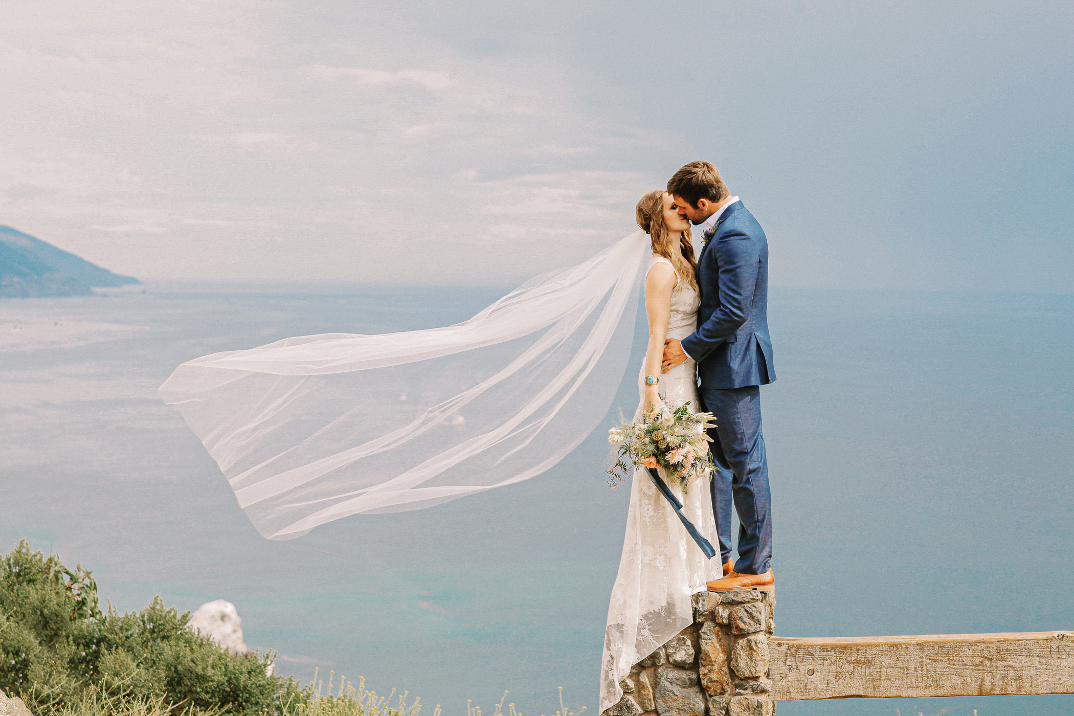 Newlywed couple overlooking the dramatic Big Sur coastline in California